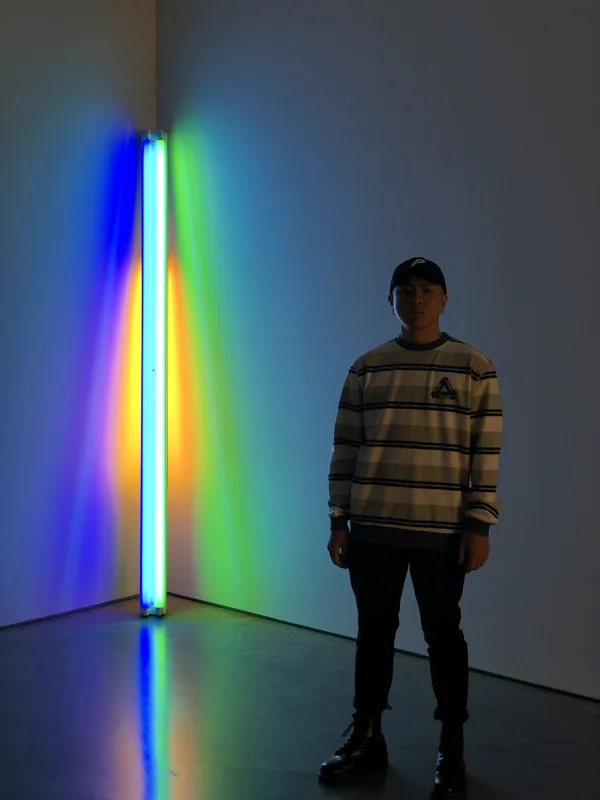 Jas standing beside a colourful light installation